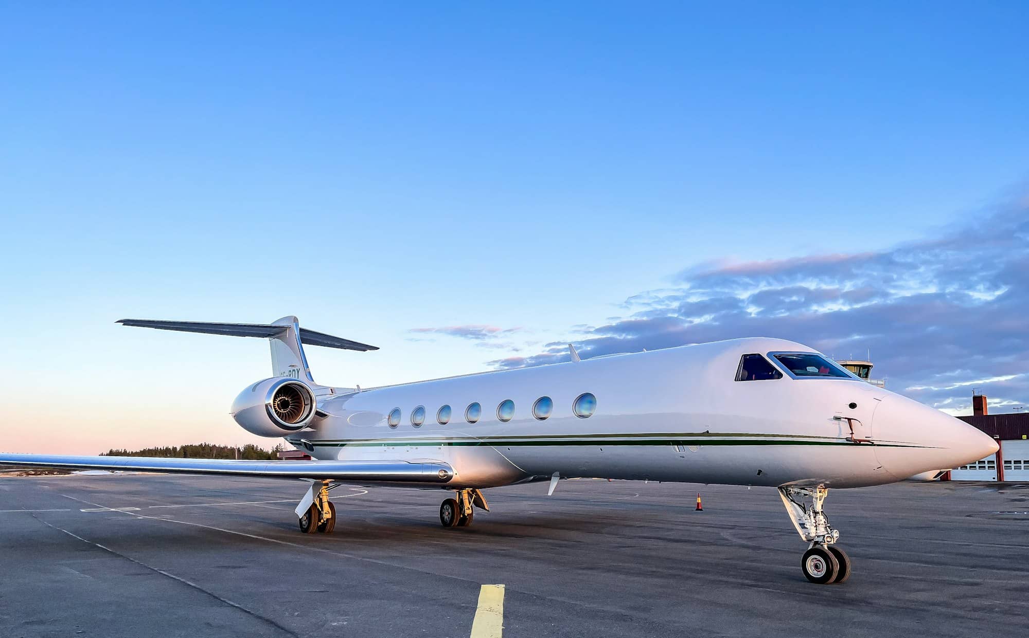 A private jet parked on an airport tarmac at dusk