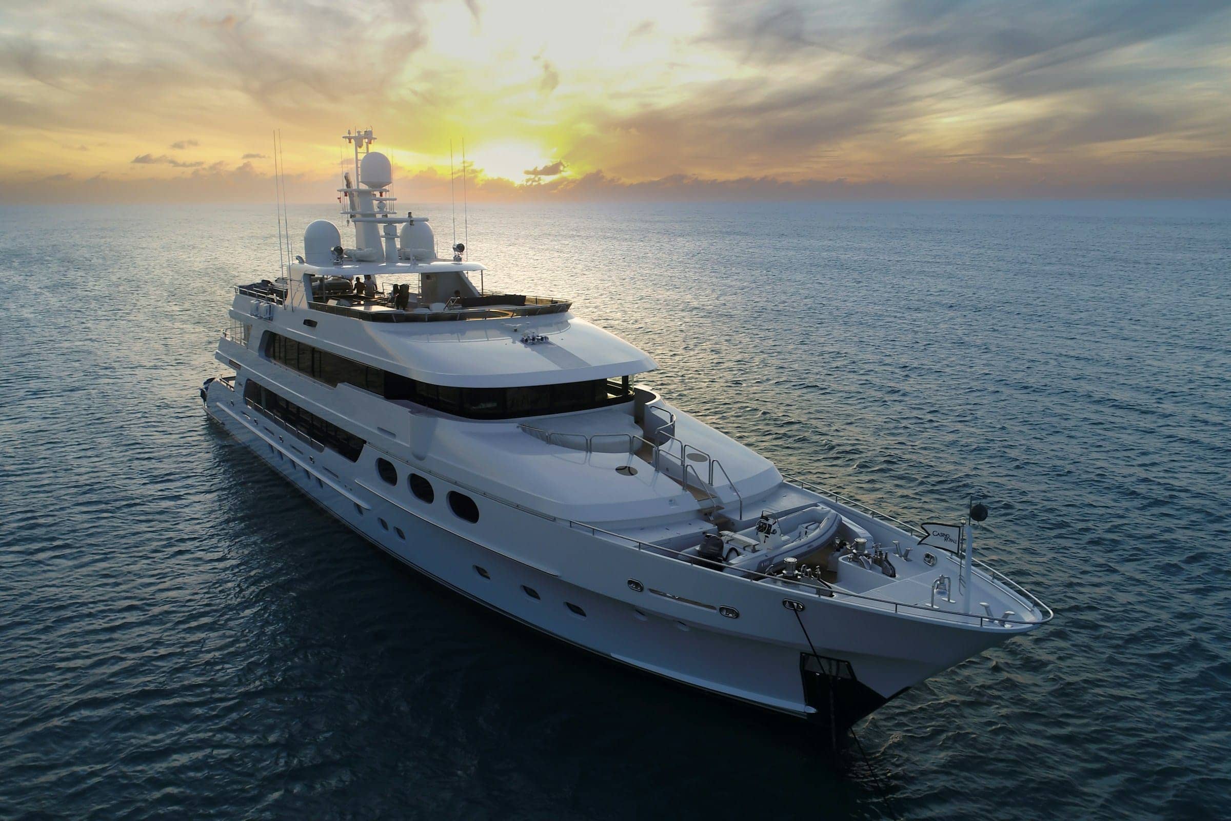 A superyacht underway at sunset, seen from the water
