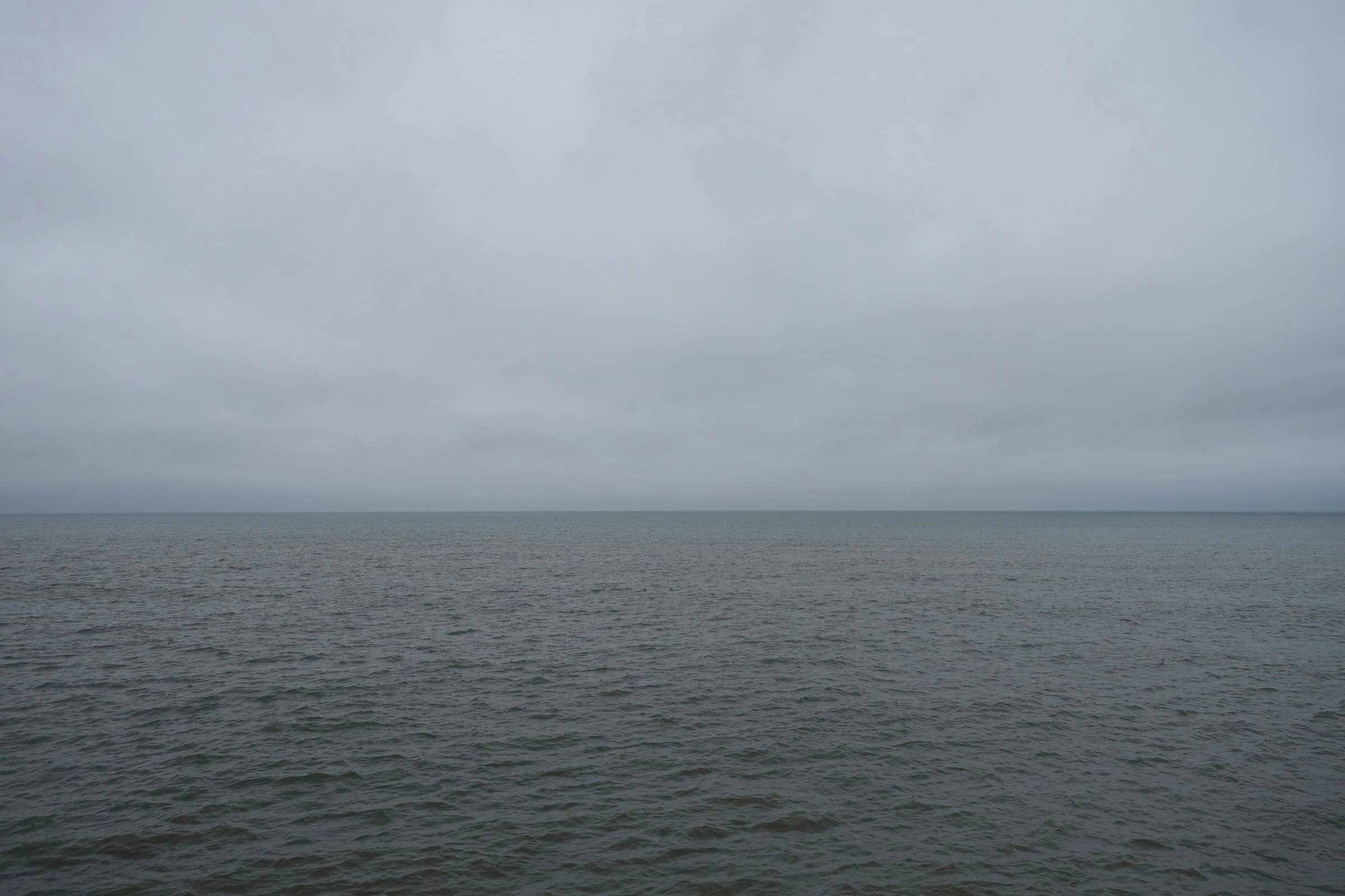 A flat, overcast gray-green gulf under a heavy sky