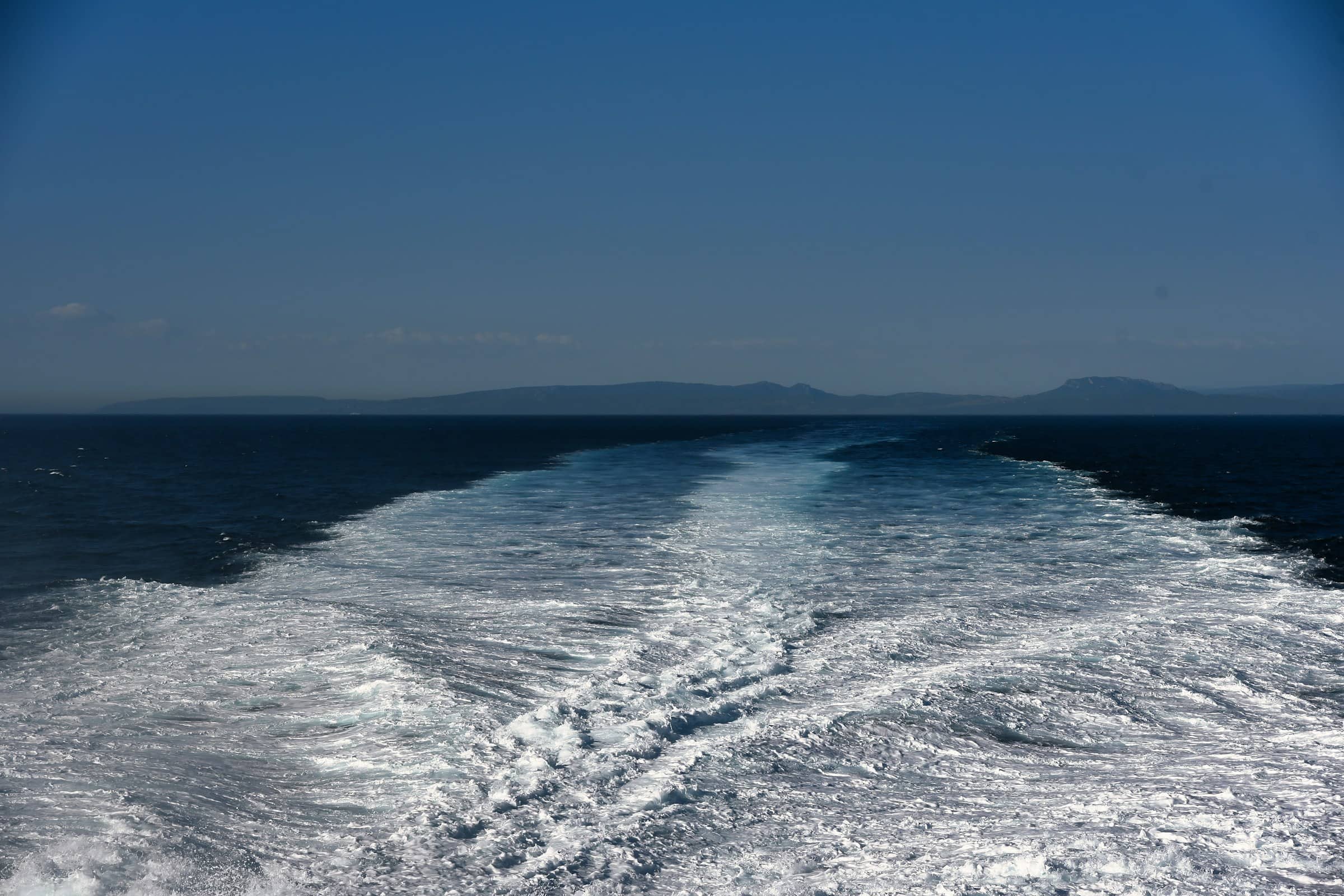 A small group aboard a boat on calm gulf water under an open sky
