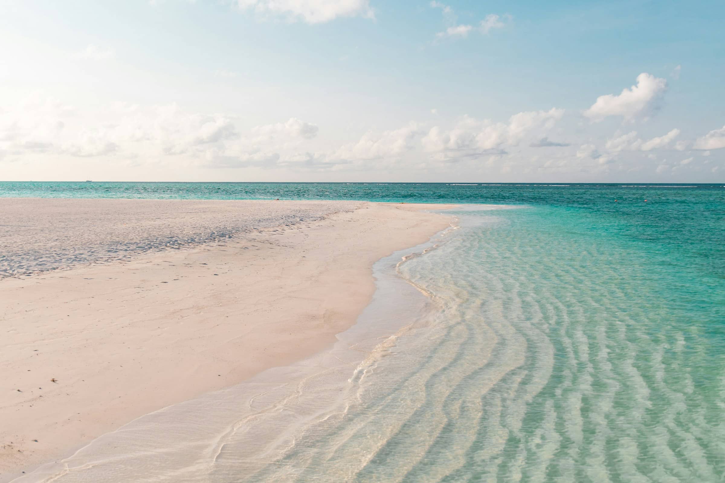 Clear rippled shallows running over white sand beside an empty beach