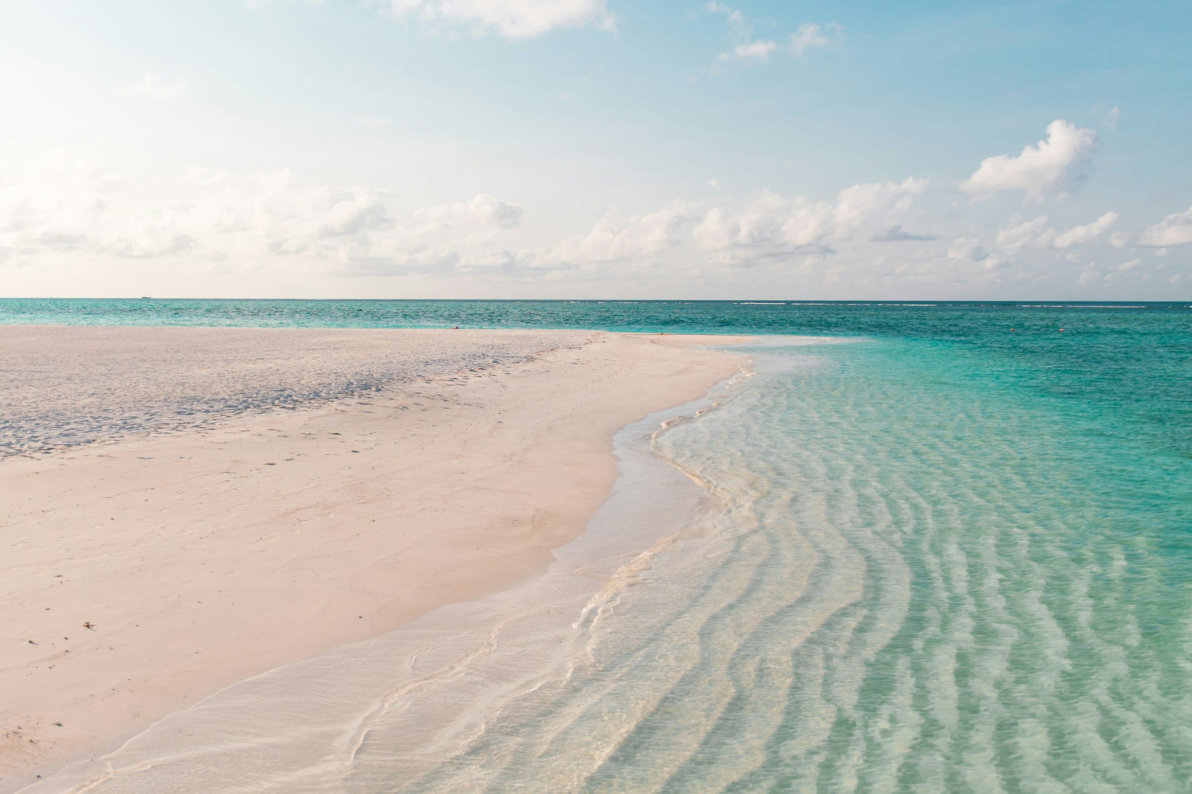 Clear rippled shallows running over white sand beside an empty beach