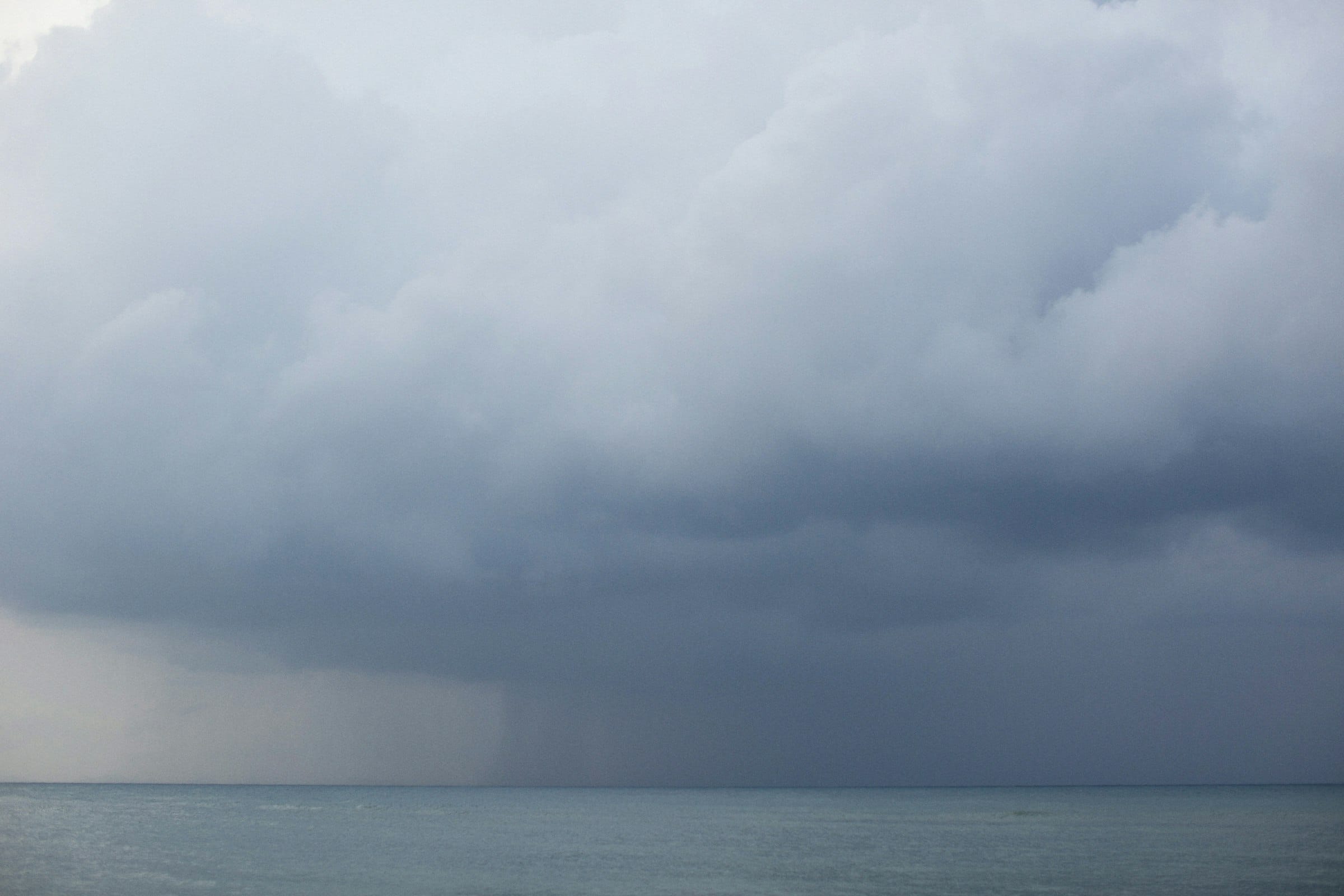 A column of rain over a calm gulf horizon