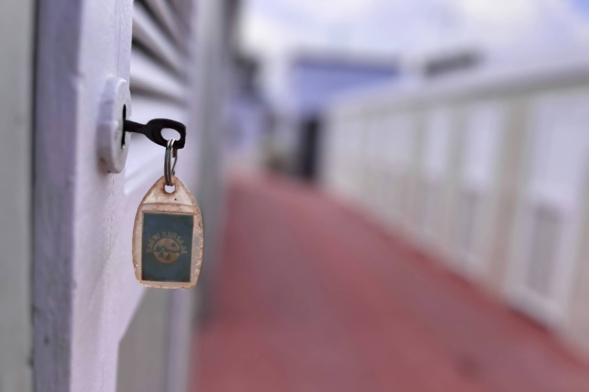 A key left in a white door, a worn fob hanging from it