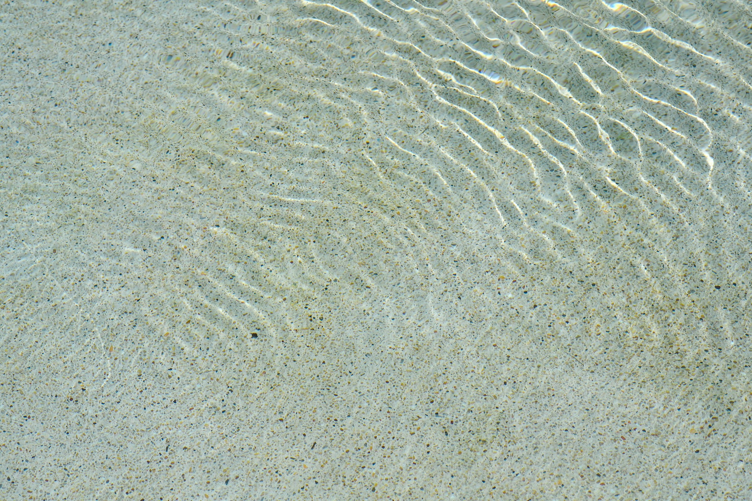 Glassy, clear knee-deep water over rippled sand
