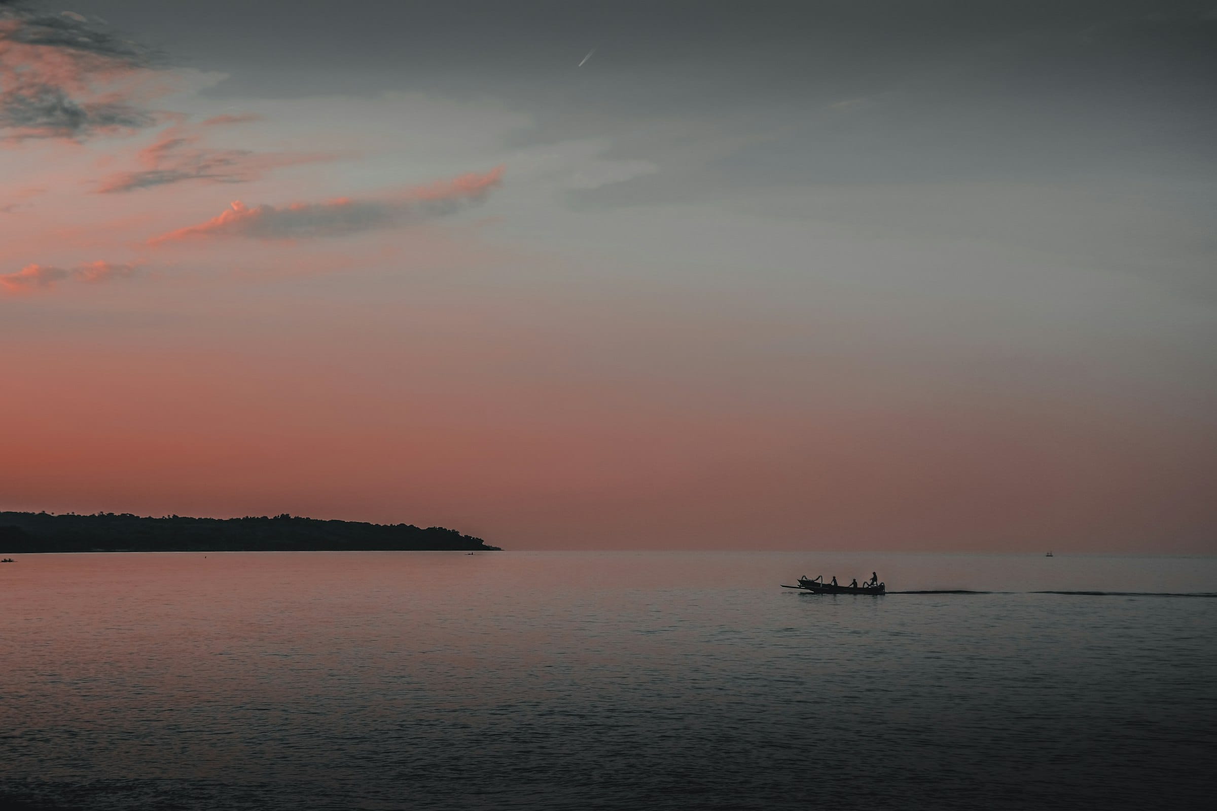 A small skiff in silhouette on calm inlet water at dusk