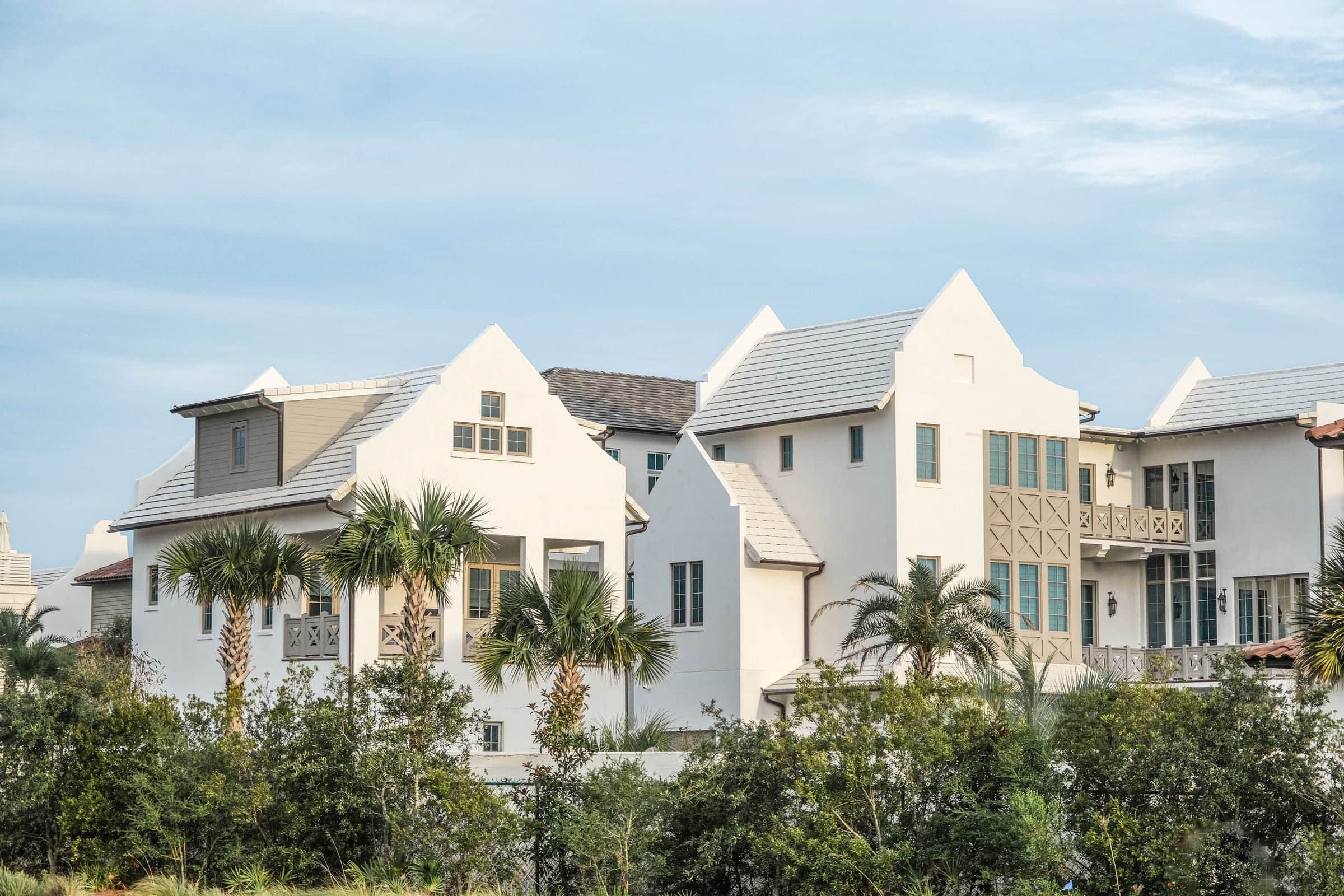 White stucco gables and parapet rooflines at Alys Beach in warm light, sabal palms rising against the facades